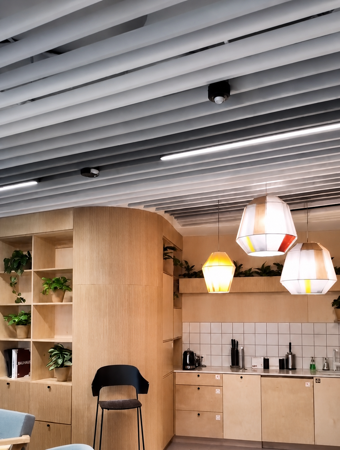 Warm residential shared space with pale linear ceiling baffles